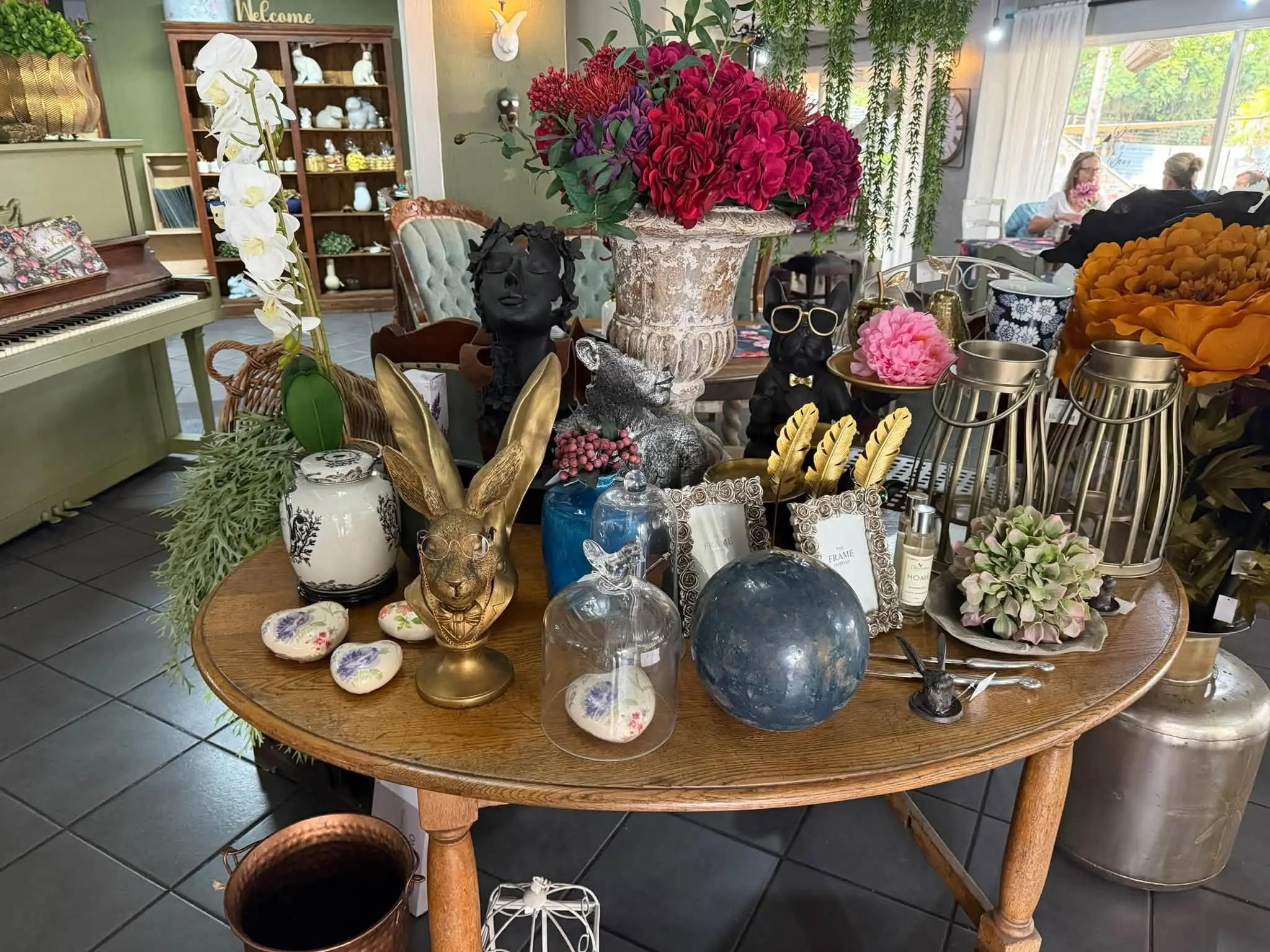 A round table in the shop with golden hares, glass domes and flowers